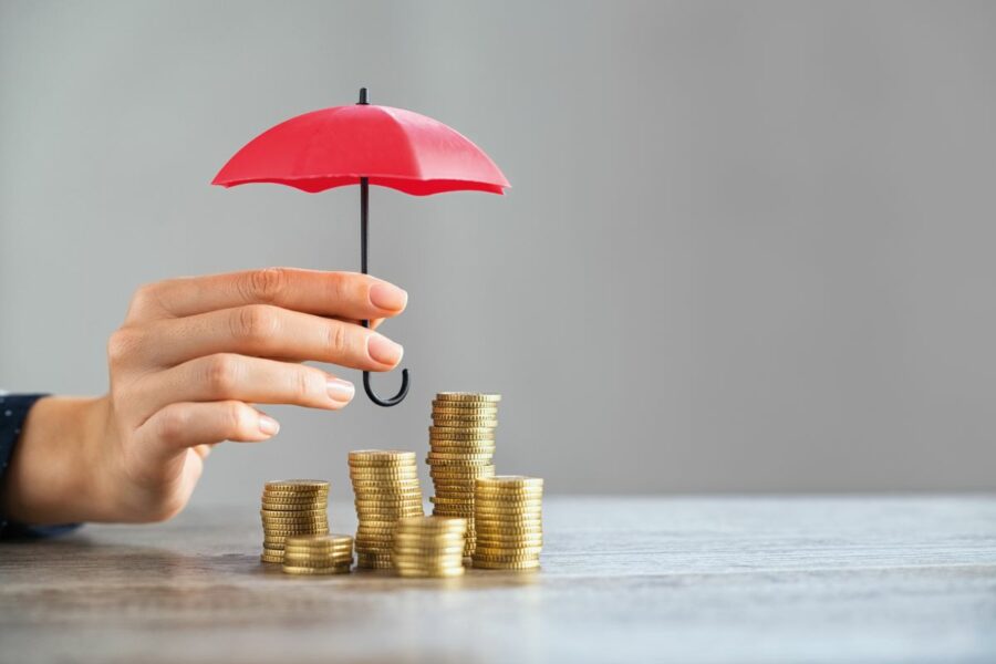 financial security concept, hand holds umbrella over coins